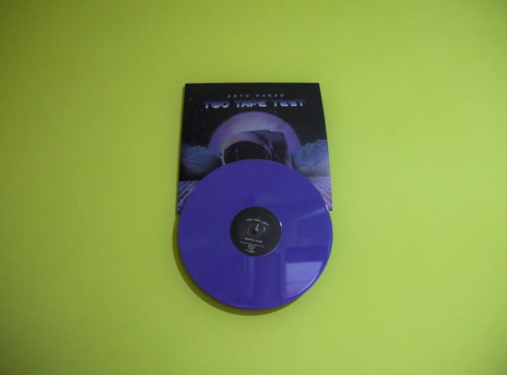 Two Tape Test vinyl record by Asto Pasar, with a purple LP and space-themed cover art on a lime green wall — wall-mounted minimalist record display.